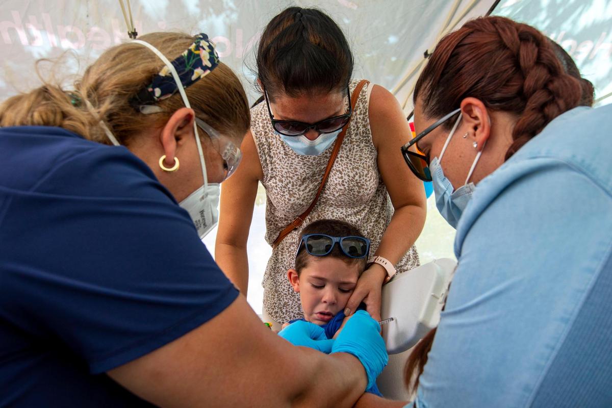 A healthcare worker, left, administers a Pfizer COVID-19 vaccine to Giam Diaz, 3, as his mother Ismarai Rodriguez, 37, center, and his aunt Natalie Leon, 30, right, hold him at the Nomi Health Mobile Health Unit inside Tropical Park in Miami, Florida, on Saturday, June 25, 2022. On Saturday, Miami-Dade County began offering the free COVID vaccines to children under 5, the last group to be authorized to receive a vaccine.
