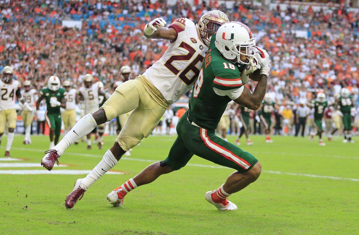 Miami Hurricanes wide receiver Lawrence Cager (18) scores in the third quarter as Florida State Seminoles defensive back Asante Samuel Jr. (26) defends Saturday, Oct. 6, 2018, at Hard Rock Stadium in Miami Gardens.
