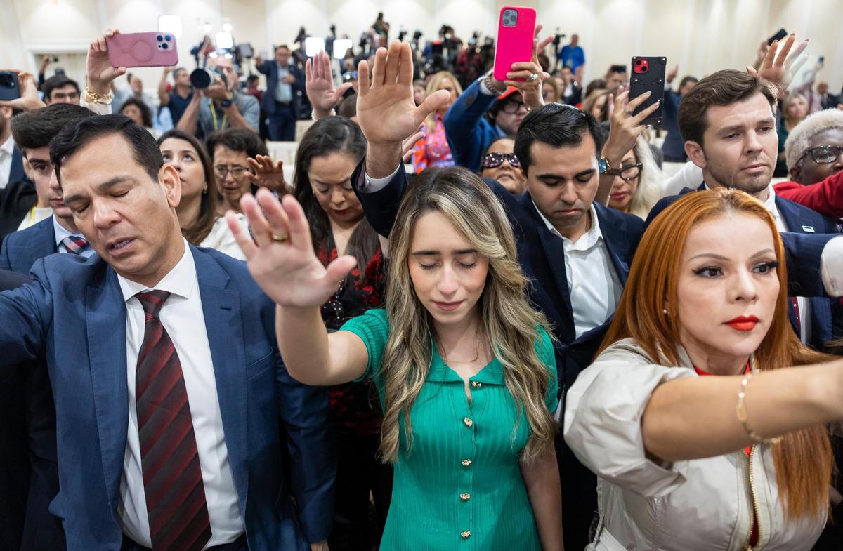 State Rep. Carolina Amesty (center) and other guests pray with Republican presidential candidate and former President Donald Trump during a roundtable discussion with local Latino leaders at Trump National Doral Miami on Tuesday, Oct. 22, 2024, in Doral, Fla.
