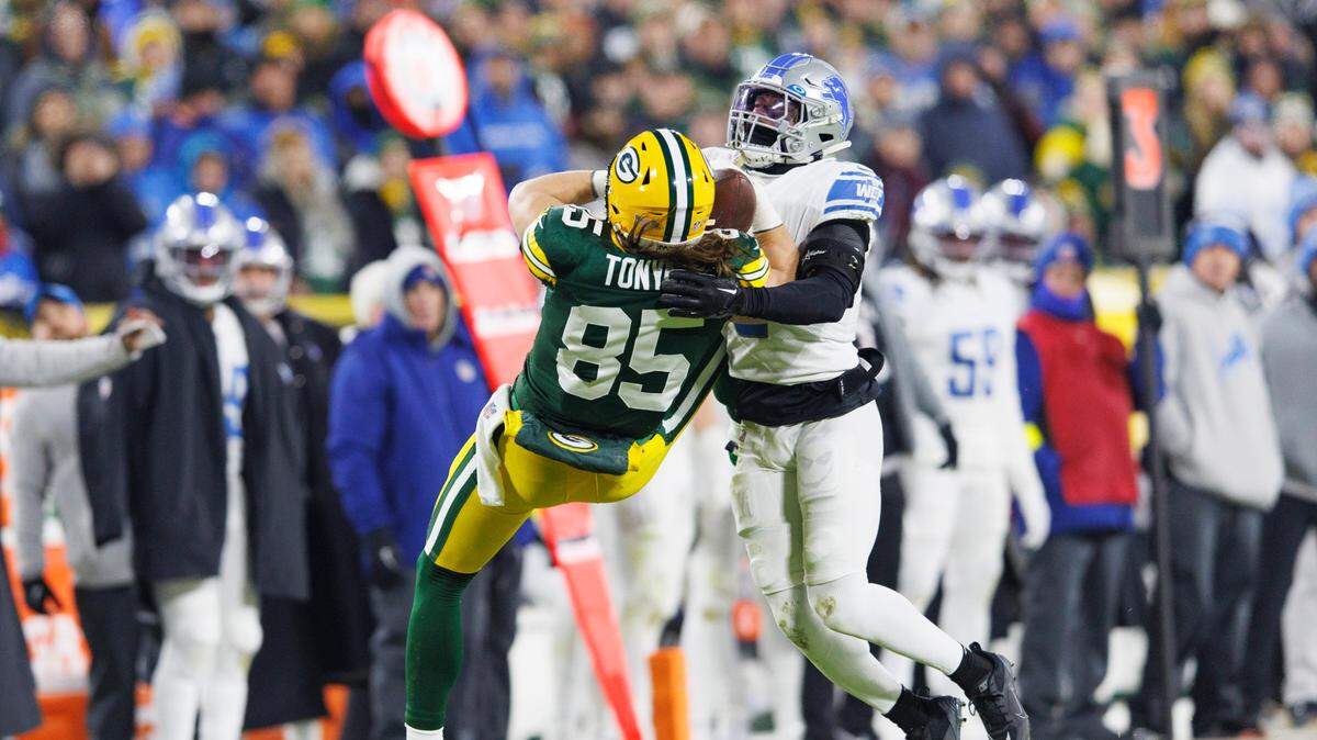 El safety de los Lions de Detroit DeShon Elliot (der.) trata de frenar al tight end de los Packers de Green Bay, en el partido celebrado el 8 de enero de 2023.