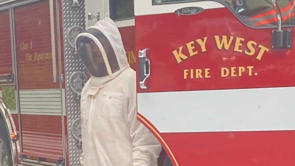A Key West firefighter exits a truck donning a bee suit Wednesday, Aug. 16, 2023. A swarm of bees forced officials to divert traffic at the entrance to city, according to police.