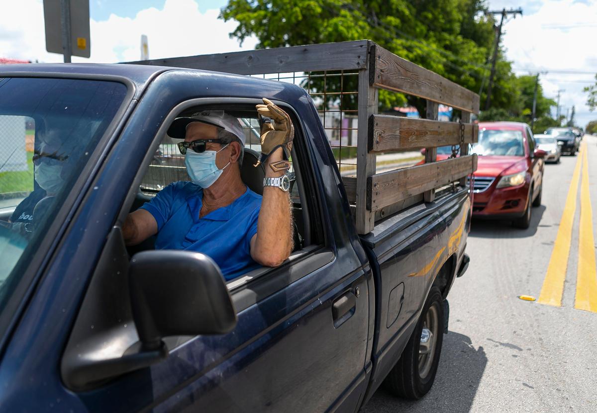 Jesus Gonzalez, 68, waits in his car to receive an unemployment form for his wife near the John F. Kennedy Library in Hialeah, Florida, on Tuesday, April 7, 2020.