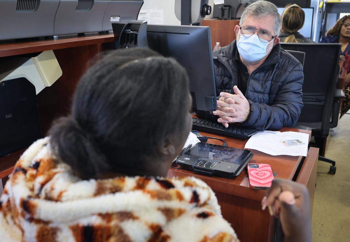 FLHSMV employee Alberto Ghisays, center, assist a TPS recipient in temporarily renew her license during a driver's license renewal event for Haiti's TPS recipients was held at Carver Ranches Library in West Park, Florida, on February 26, 2026, to help Haitian immigrants and others update their licenses.