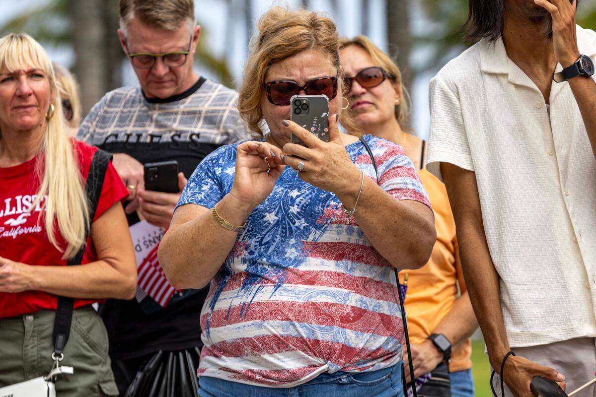 A woman takes cell phone photos during the 16th Annual Veterans Day Parade off Ocean Drive on Monday, Nov. 11, 2024, in Miami Beach, Fla.