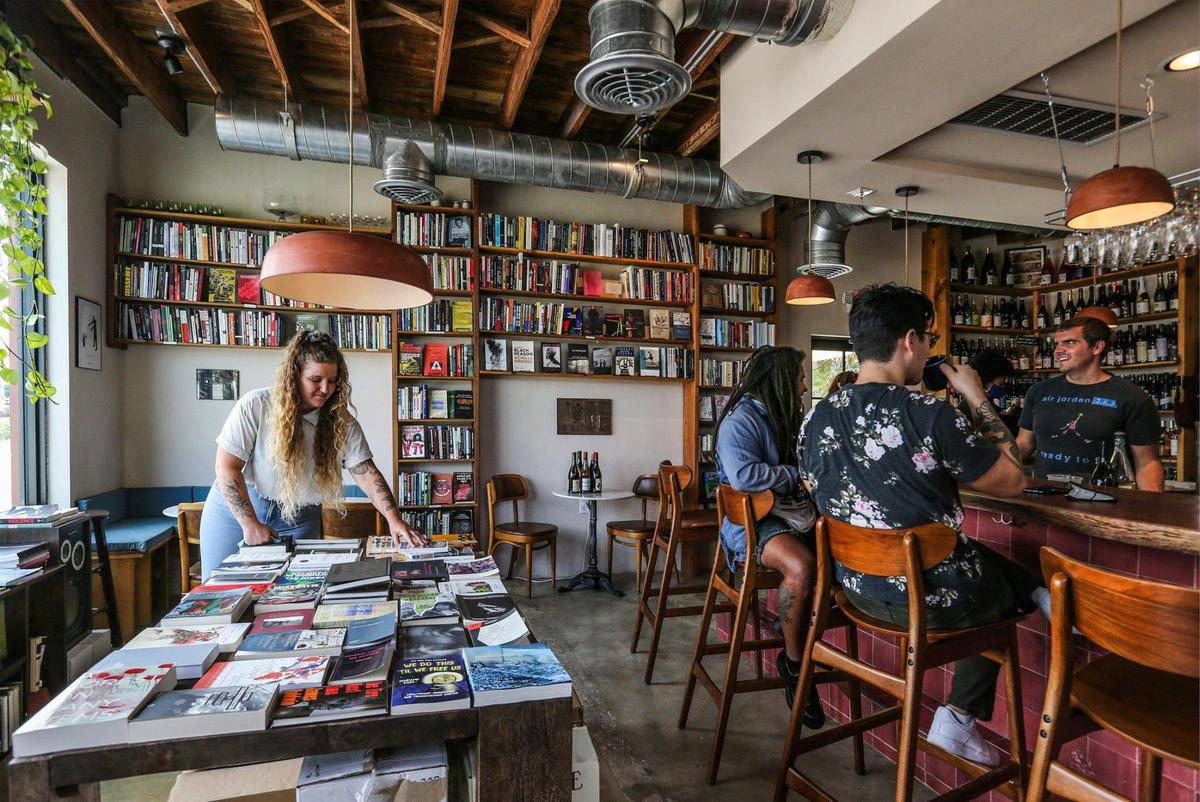 Audrey Wright unpacks books as co-owners Sef Chesson, Ben Yen and Brian Wright drink coffee at Paradis books & bread in North Miami.