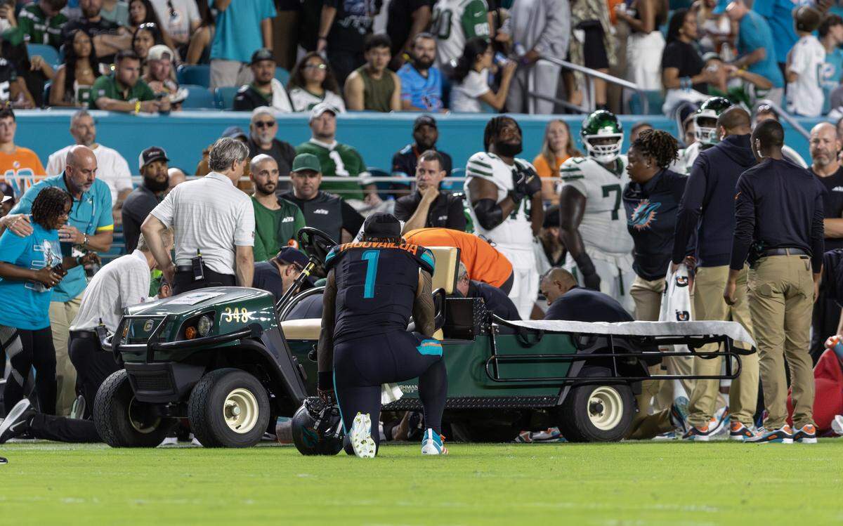 Miami Dolphins quarterback Tua Tagovailoa (1) kneels beside wide receiver Tyreek Hill (10) as Hill prepares to be carted off the field after suffering an injury during the second half of an NFL game against the New York Jets at Hard Rock Stadium on Monday, Sept. 29, 2025, in Miami Gardens, Fla.