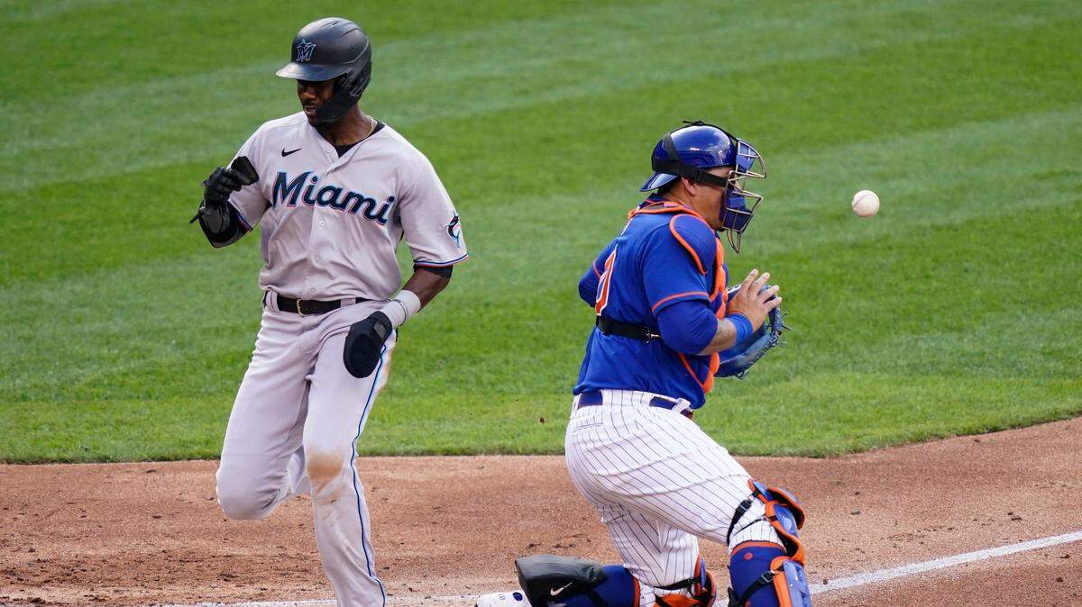 Miami Marlins’ Lewis Brinson, left, scores against New York Mets catcher Wilson Ramos, right, on a two-run single hit by Miguel Rojas in the second inning during the first baseball game of a doubleheader, Tuesday, Aug. 25, 2020, in New York. (AP Photo/John Minchillo)