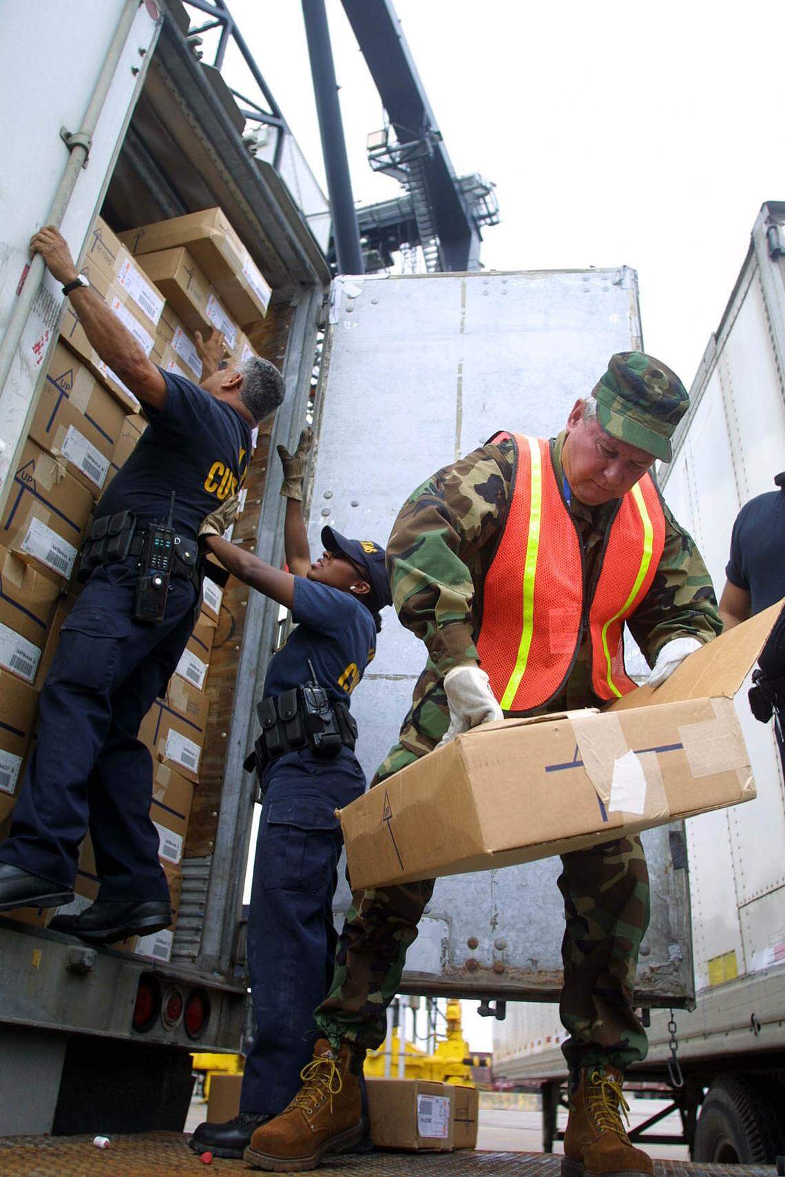 FOR BROWARD -- 01/03/02 -- SENATOR BOB GRAHAM WORK DAY AS PORT SECURITY -- MIAMI HERALD STAFF PHOTO BY CHUCK FADELY -- U.S. Senator Bob Graham, right, opens a box of jean shorts from Central America as he helps U.S. Customs inspectors go through a container at Port Everglades. Senator Bob Graham spent Thursday morning, January 3, 2002 working security for Port Everglades. He joined U.S. Customs agents in searching containers and then patrolled the waters of the port aboard the USCG Cutter Gannet.