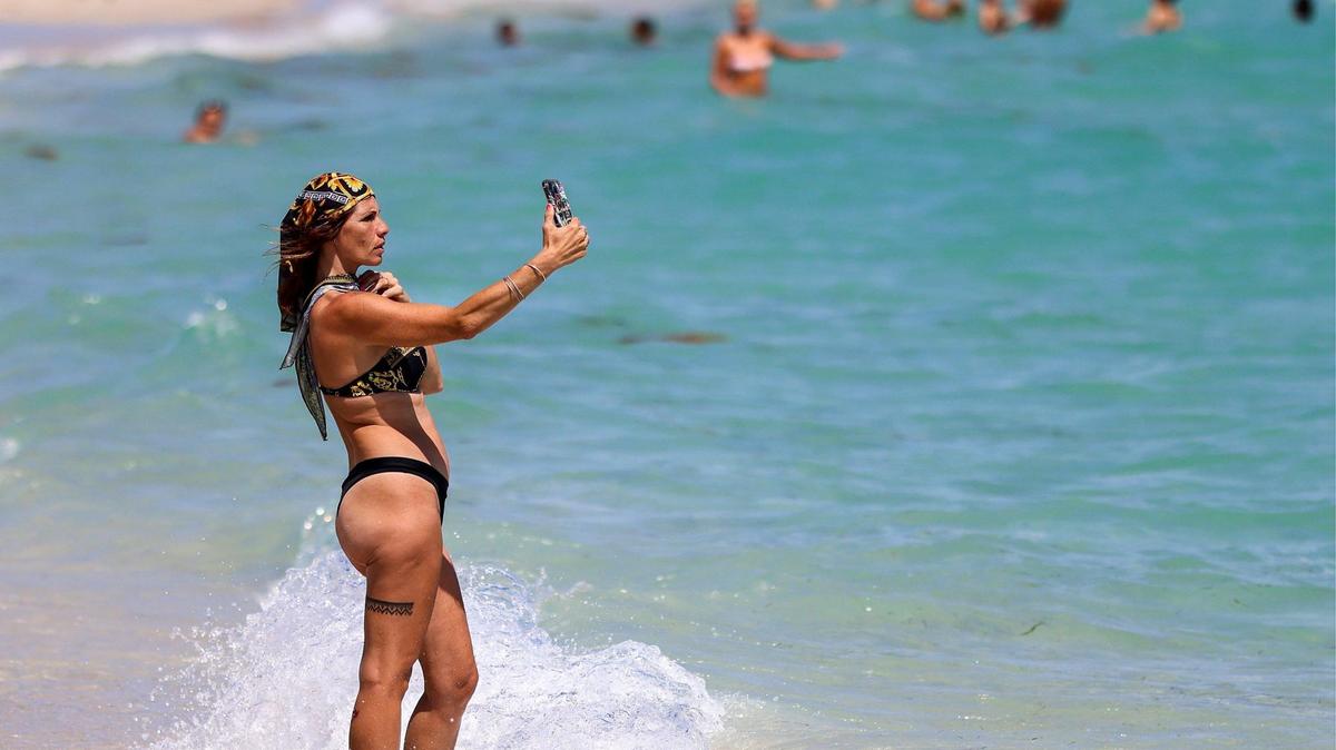 A beachgoer takes a moment to capture a selfie during perfect beach weather during Spring Break in Miami Beach, Florida on Thursday, March 13, 2025 as Spring Break kicks off this weekend. The South Florida forecast calls for temperatures to drop Monday night to the low 50s.