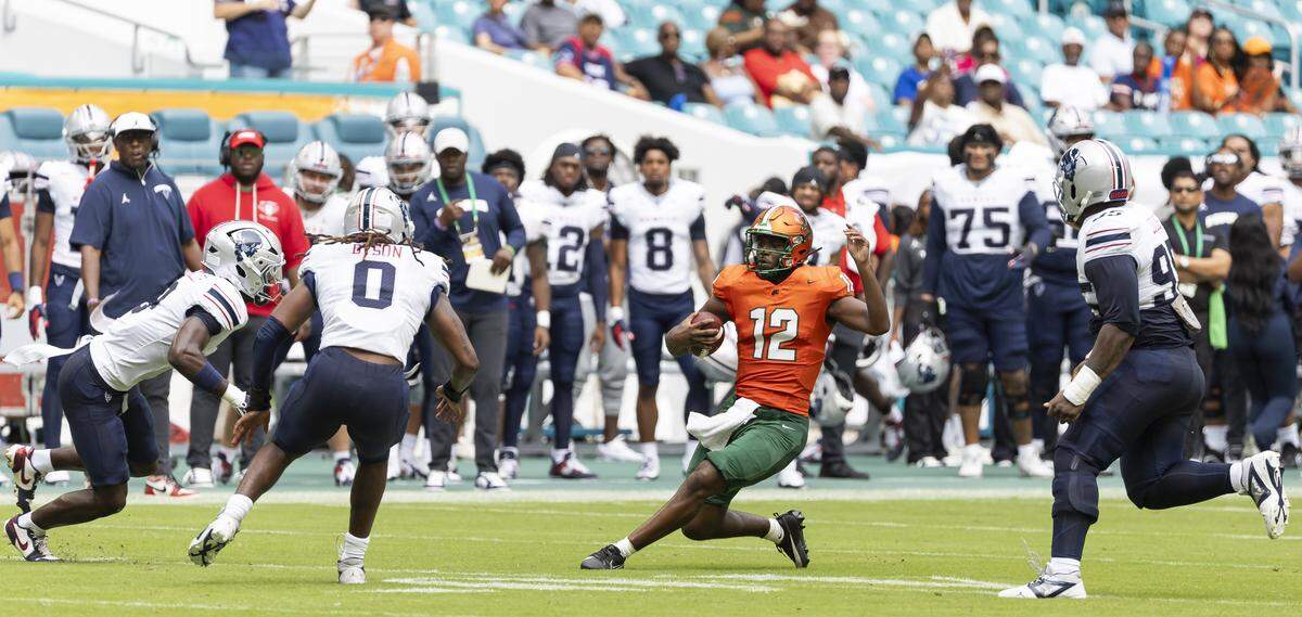 Florida A&M Rattlers quarterback RJ Johnson (12) slides with the ball as Howard Bison tight end KD Mosley (0) defends in the first half of their Orange Blossom Classic football game at Hard Rock Stadium on Saturday, Aug. 30, 2025, in Miami Gardens, Fla.