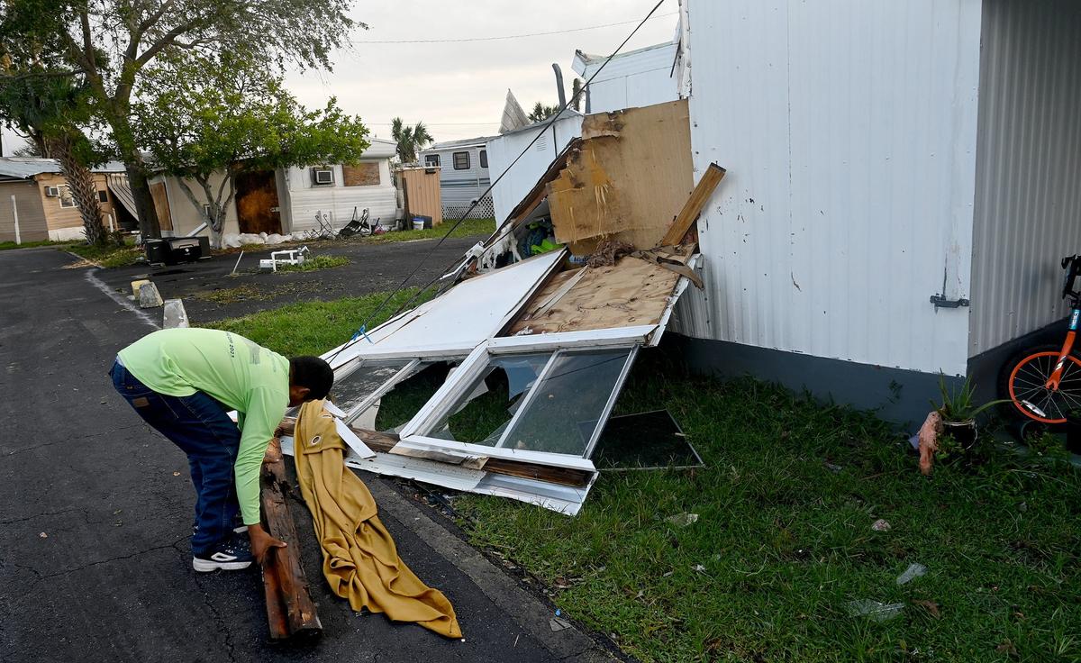 A resident of Luxor Mobile Home Park picks up belongins strewn by Hurricane Milton on Oct. 10, 2024.