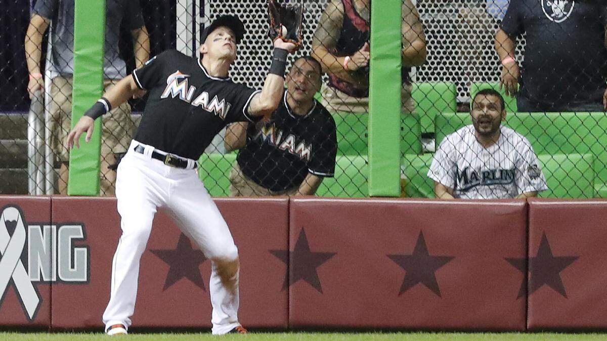 Miami Marlins left fielder Derek Dietrich catches a ball hit by Cincinnati Reds’ Joey Votto during the fourth inning of a baseball game, Friday, Sept. 21, 2018, in Miami.