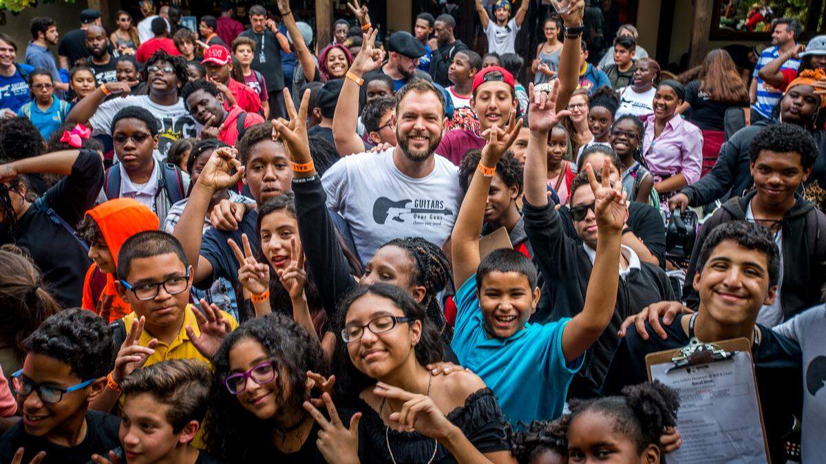 Guitars Over Guns CEO and founder Chad Bernstein (center) poses with students. The group received a 2019 CreARTE grant by the Perez Family Foundation.  