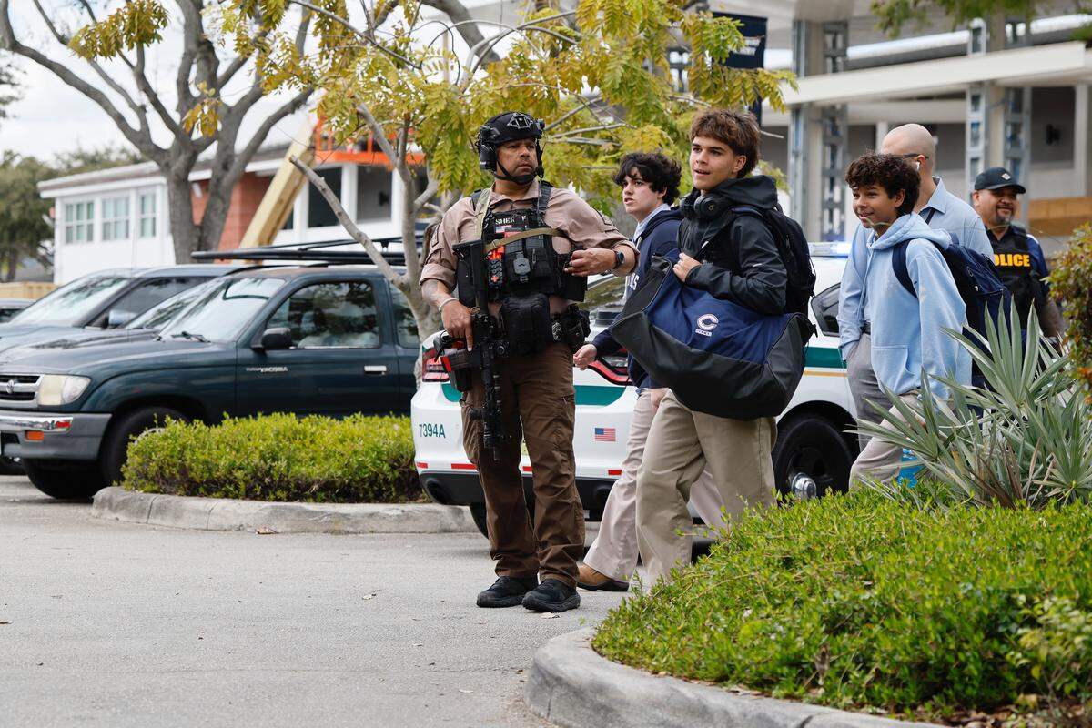 Christopher Columbus High School students walk past a Miami-Dade sheriff’s deputy after deputies respond to a call of an active shooter at the school on Southwest 87th Avenue on Wednesday, Feb. 4, 2026, in Miami. Authorities said there was no active shooter at the school. Authorities are investigating the call.