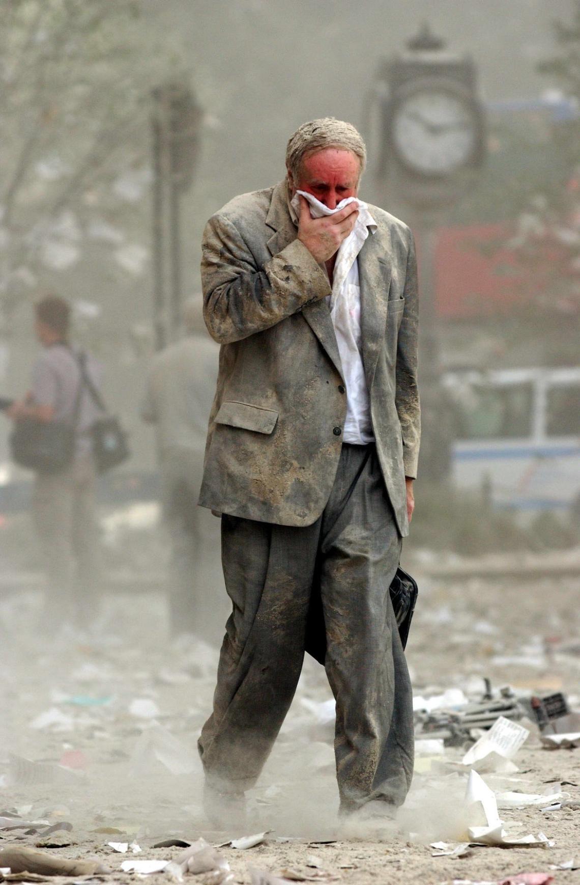 A man covers his mouth as he walks through debris after the collapse of one of the World Trade Center Towers September 11, 2001, in New York. Both towers collapsed after two passenger planes controlled by hijackers were crashed into the buildings.