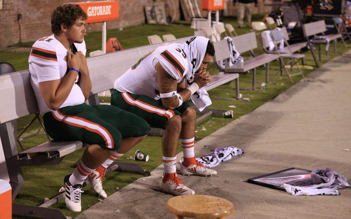 Miami Hurricanes place kicker Bubba Baxa (21) and Jordan Butler (39) sit on the bench late in the fourth quarter at Virginia’s Scott Stadium in Charlottesville, VA on Saturday, October 13, 2018.