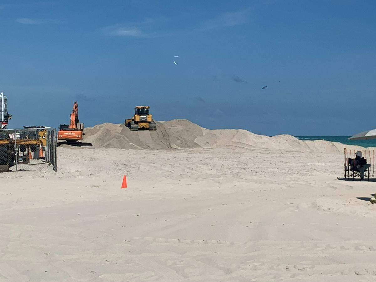 Trucks work atop piles of sand near 46th Street in Miami Beach as part of a beach renourishment project on Friday, Feb. 24, 2023.