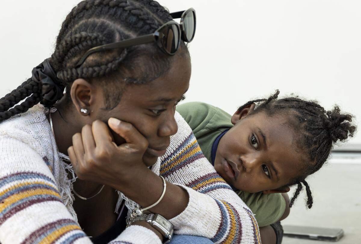 Rhylan Hall, 2, listens to his mother, Nathalia Hall, 18, speak as they sit near the Lotus House Women's Shelter on Tuesday, Nov. 18, 2025, in Miami, Fla.
