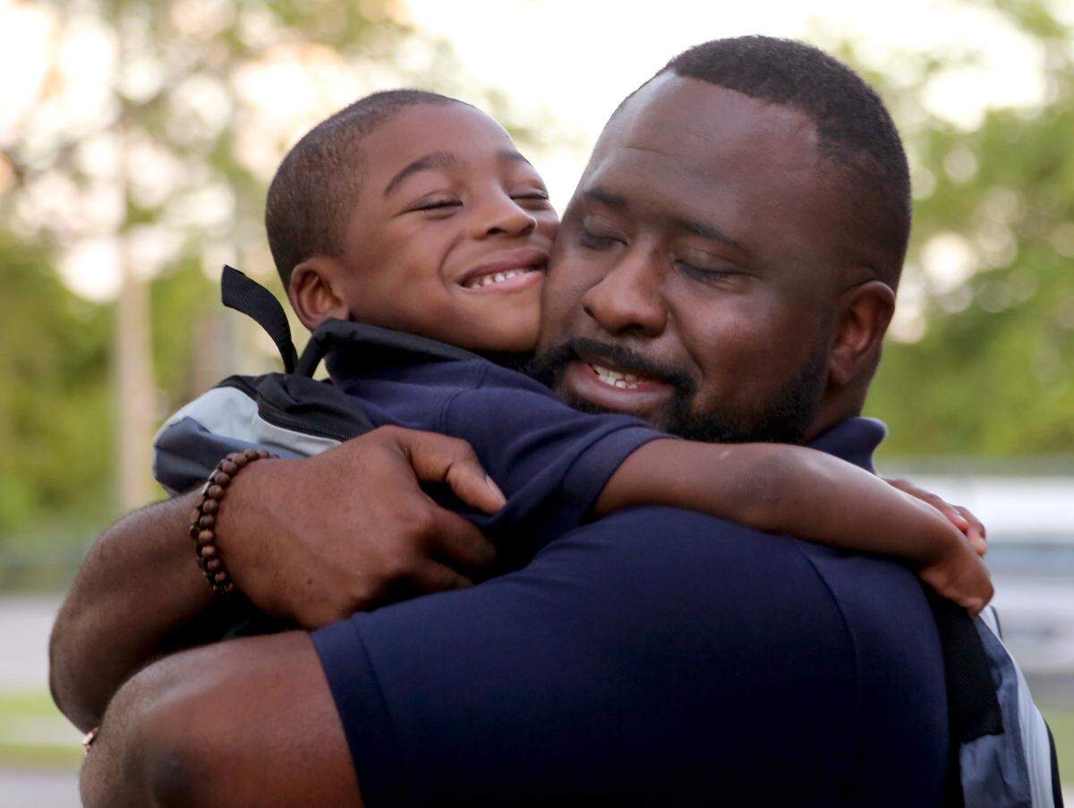 Leroy Venisee, 5, is greeted with a big hug by Justin Leach, a partner teacher who visited him at home prior to the first day of school.  Kindergarten students were greeted with the sounds of clappers, cheers, and kazoos as students and parents were greeted by the faculty and the staff of KIPP Sunrise Academy on the first day of school on Monday, August 20, 2018.