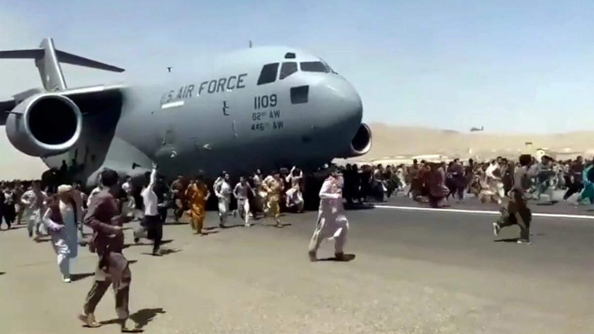 Hundreds of Afghans run alongside a U.S. Air Force C-17 transport plane as it taxis down the runway in Kabul.