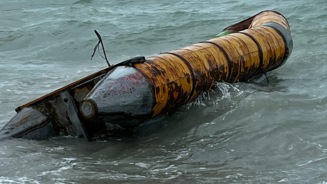 A homemade raft with honey barrels surrounding the hull floats in the shallow water on the beach of Key Biscayne Sunday, Jan. 9, 2022.