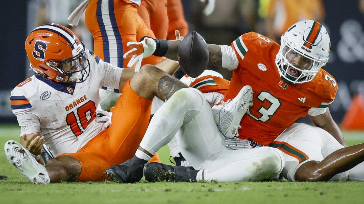 After Syracuse Orange quarterback Rickie Collins (10) is sacked, Miami Hurricanes defensive lineman Akheem Mesidor (3) strips the ball in the second half of an NCAA football game at Hard Rock Stadium in Miami Gardens, Florida on Saturday, November 8, 2025.