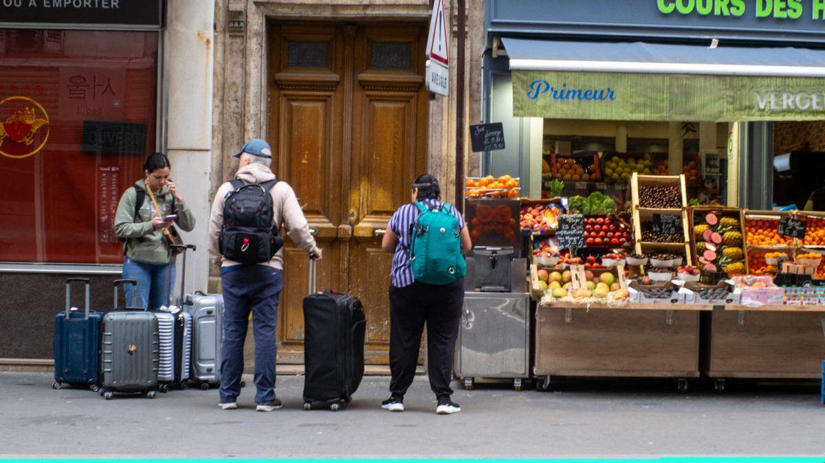 Tourists with suitcases in front of an apartment looking for their Airbnb in Paris, France, June 2, 2024.