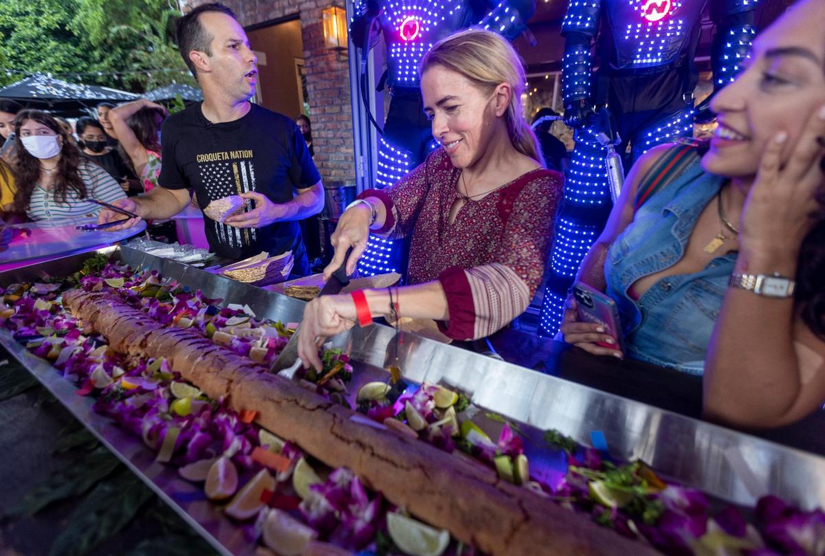 Miami, Florida, October 1, 2021 - Miami-Dade County Commissioner, Raquel Regalado, center, cuts the world’s longest croqueta to be served to the public. Sergio’s Cuban Restaurant celebrated the fourth annual Croqueta Day on Friday with a 6-foot-long crispy croqueta.