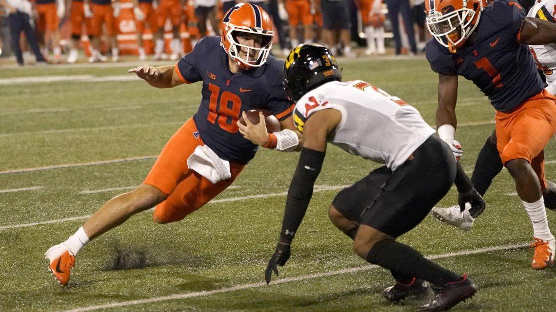 Illinois quarterback Brandon Peters makes a cut as Maryland defensive back Nick Cross comes up to make a tackle during the first half of an NCAA college football game Friday, Sept. 17, 2021, in Champaign, Ill.