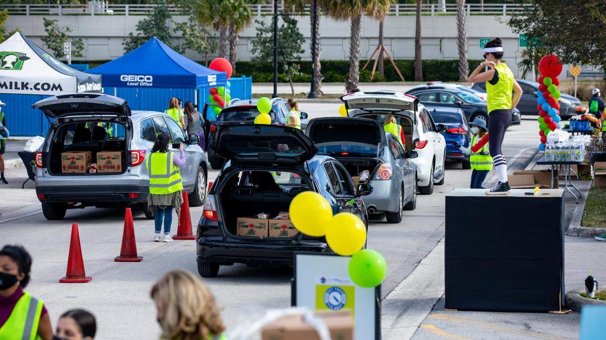Volunteers and staff stock the trunks of guests in line for the contactless drive-thru delivery system hosted by Miami Children’s Museum and Farm Share, to provide families in South Florida experiencing food insecurity with access to nutritious foods and resources that inspire a healthy lifestyle in the midst of the COVID-19 pandemic at Watson Island in Miami, Florida, on Saturday, Jan. 30, 2021. The event is sponsored by Florida Dairy Farmers, Florida Healthy Kids Corporation, Geico North Miami and The Kirk Foundation.