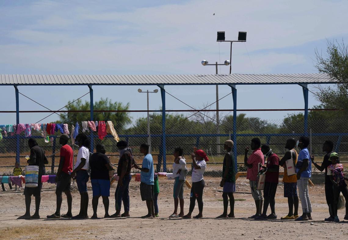 Migrants, many from Haiti, line up to receive food at an improvised refugee camp at a sport park in Ciudad Acuña, Mexico, Wednesday, Sept. 22, 2021