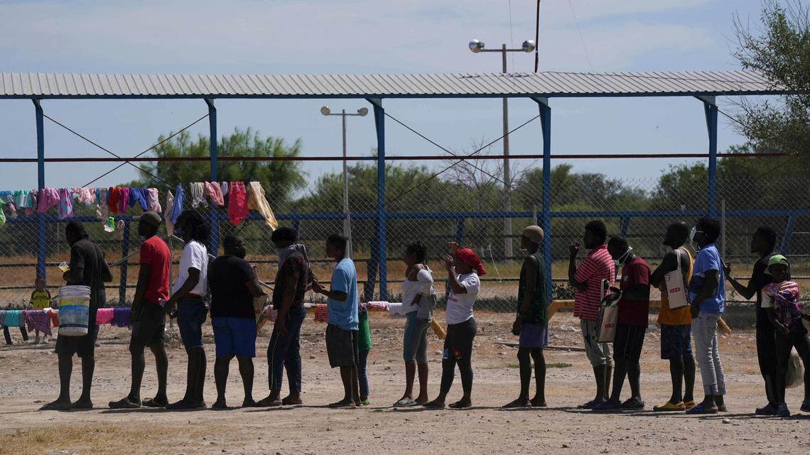Migrants, many from Haiti, line up to receive food at an improvised refugee camp at a sport park in Ciudad Acuña, Mexico, Wednesday, Sept. 22, 2021.