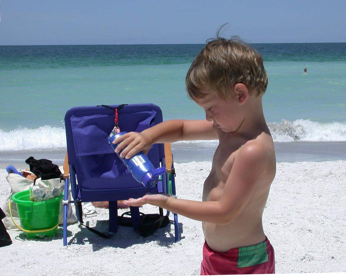 Patrick Saunders, 3, puts on sunscreen before heading to the water at Manatee Public Beach. Always make sure you apply at least a shot glass full of sunscreen to cover your body, dermatologists say.