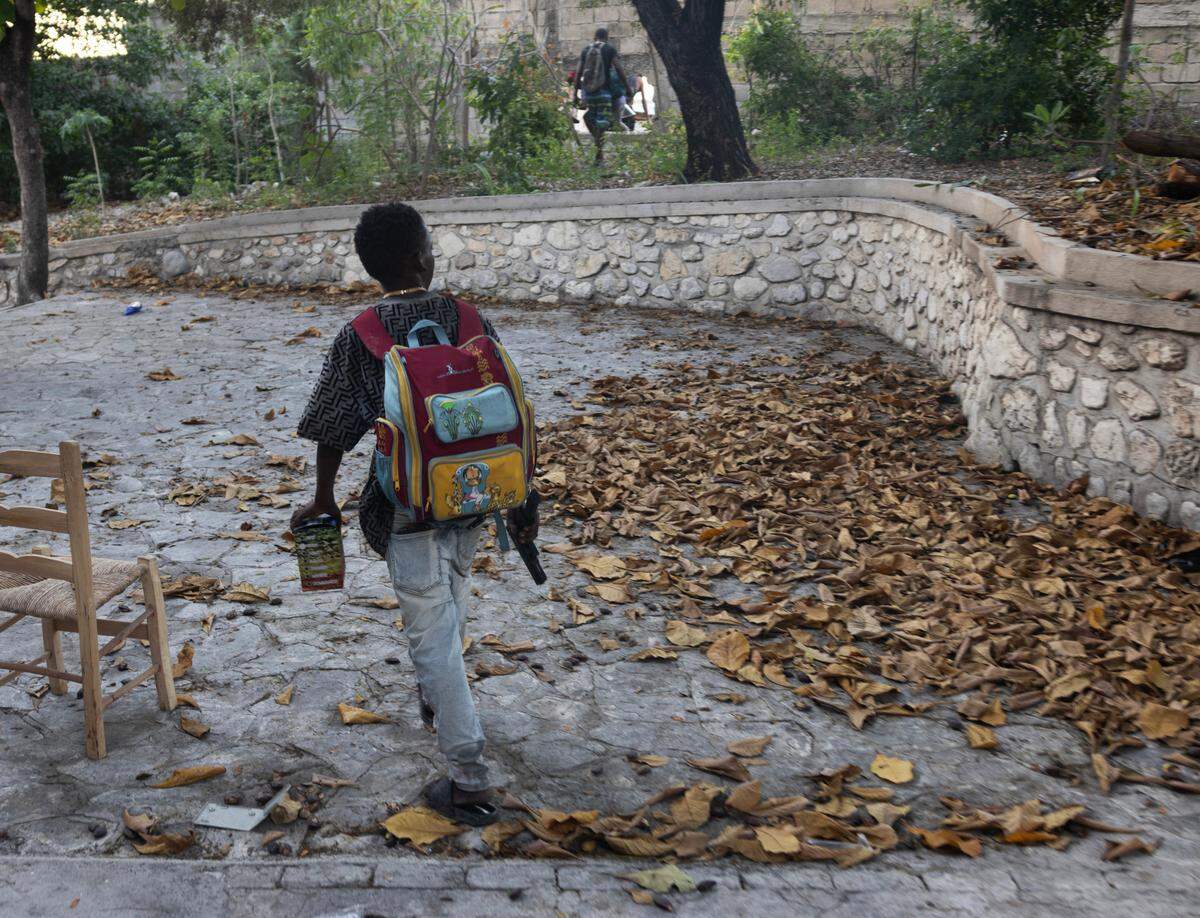 A nine-year-old gang member walks with a pistol after he and other gang members raided a neighborhood of Port-au-Prince, Dec. 6, 2024.