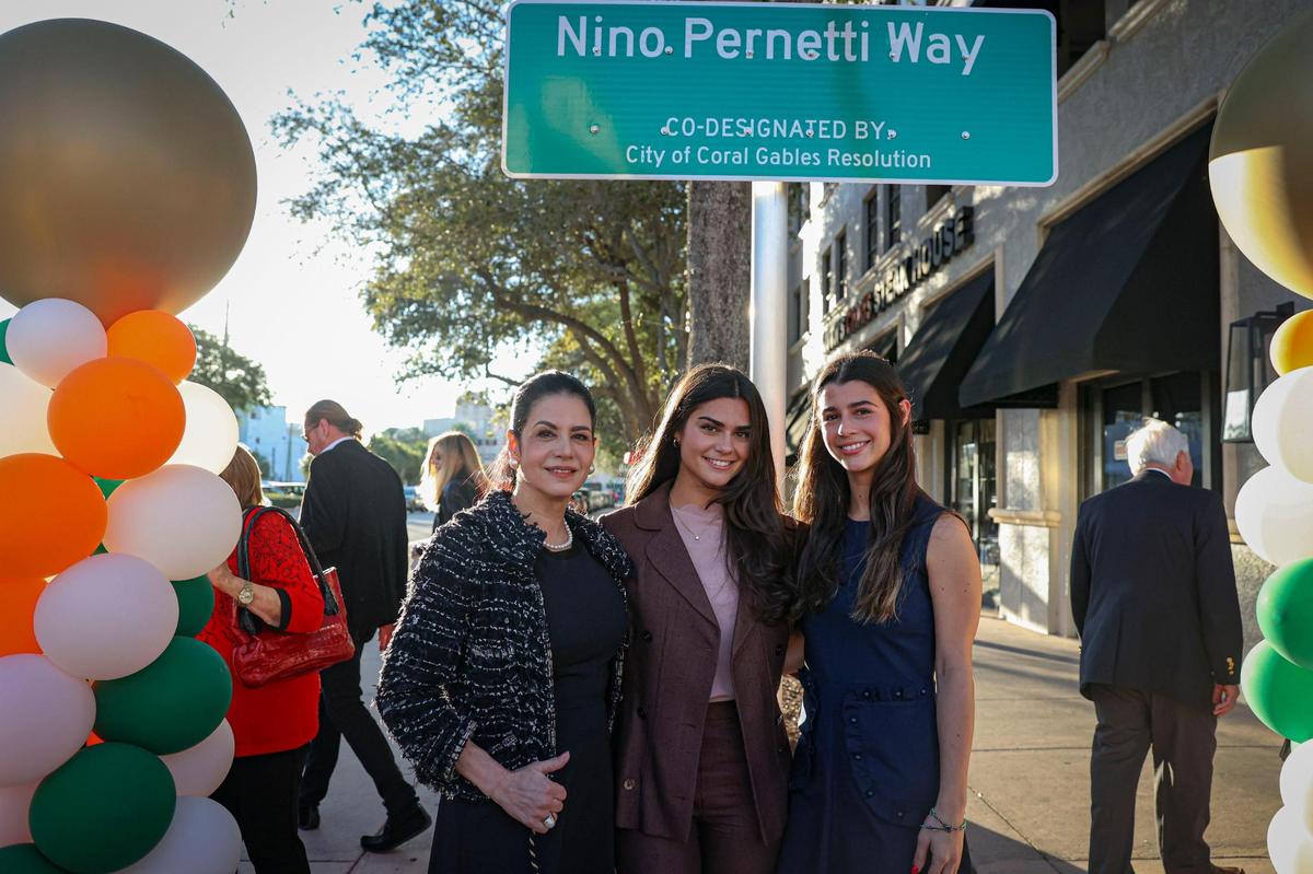Marlen Pernetti, left, and her daughters Tatiana and Katerina, right, pose in front of the street sign dedicated to Nino Pernetti, the late owner of Coral Gables restaurant Caffe Abbracci.