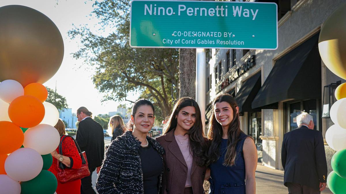 Marlen Pernetti (l) and her daughters Tatiana and Katerina (r) pose in front of the street sign dedicated to Nino Pernetti, the late owner of Coral Gables restaurant Caffe Abbracci.