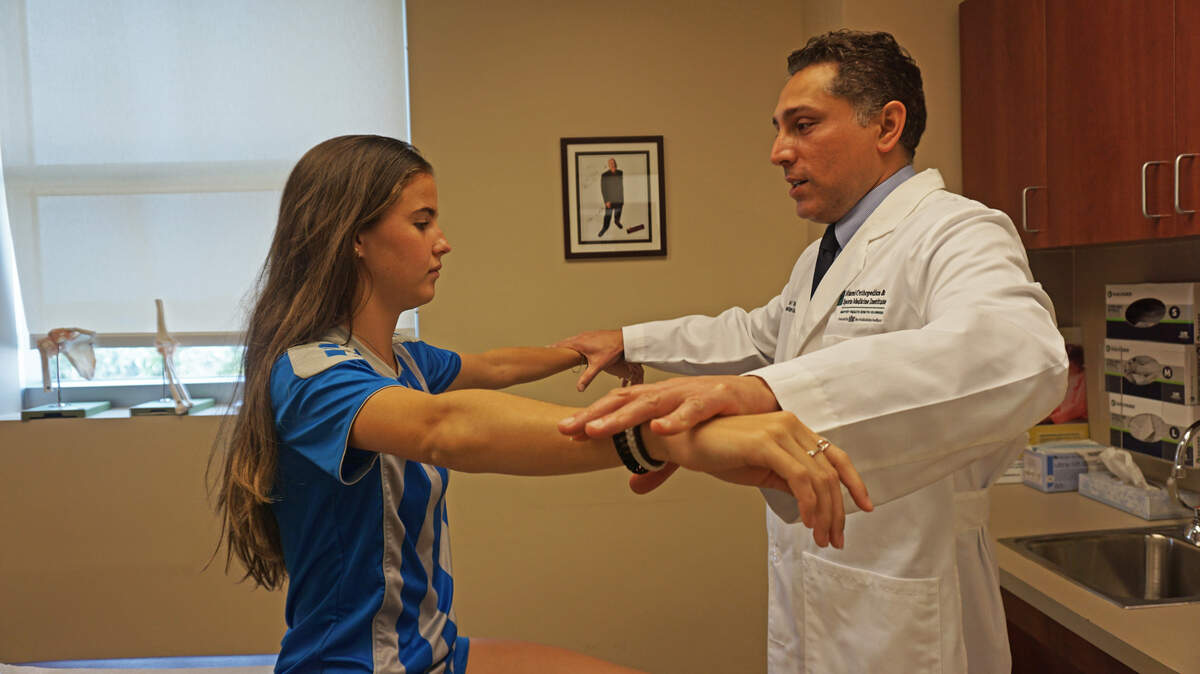 Dr. Gautam Yagnik, an orthopedic surgeon with Miami Orthopedics & Sports Medicine Institute, examines Karina Dougery, 17, after performing her arthroscopic meniscus repair. She has played soccer for eight years, and wants to play in college.