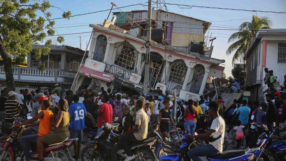 People gather outside the Petit Pas Hotel, destroyed by the Aug. 14 earthquake in Les Cayes, Haiti.