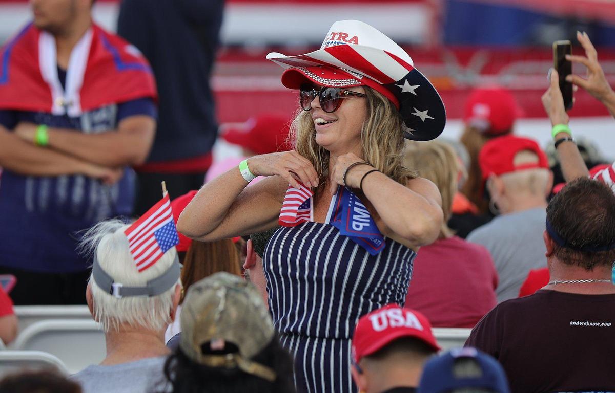 A Trump supporter adjust flags she tucked into her shirt at a rally at the Youth Fairgrounds in Miami. On Sunday, November 6, 2022 former President Donald Trump and a collection of other national and local Republicans campaign with U.S. Sen. Marco Rubio on the eve of the Nov. 8 election.