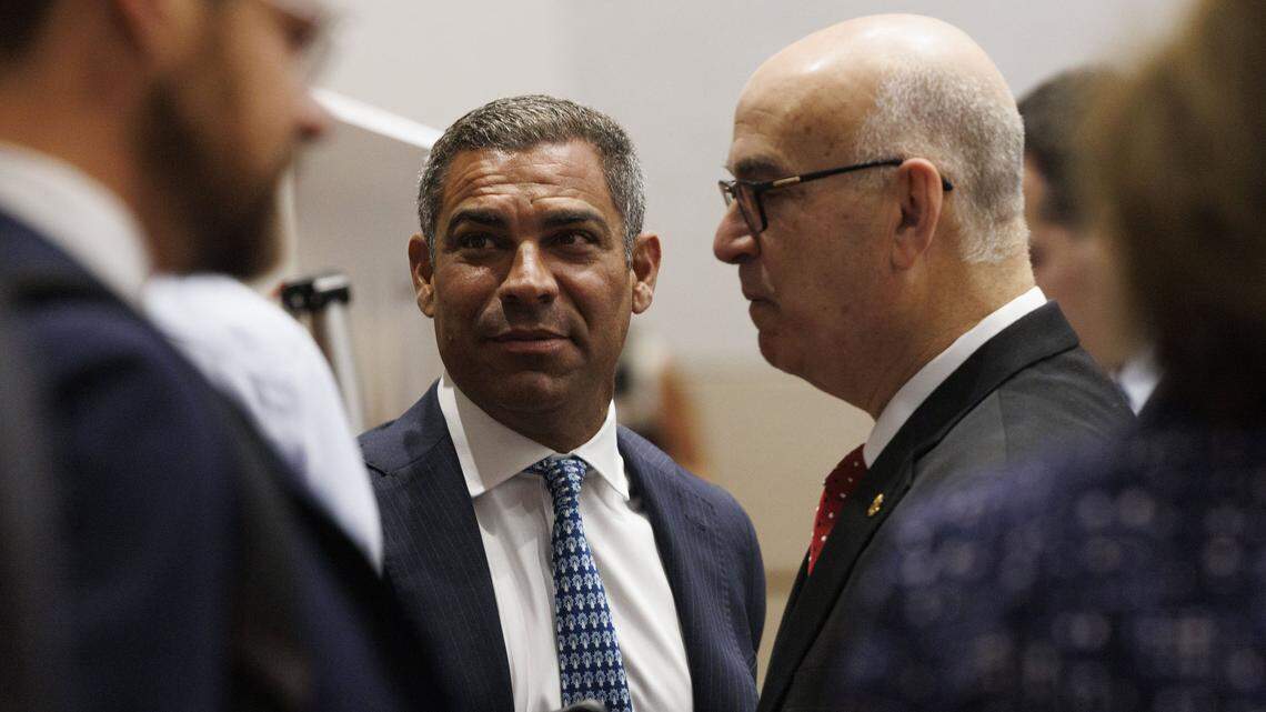 Mayor Francis Suarez, center, talks with Emilio González, right, and others before a hearing at the Third District Court of Appeal for a case González brought against the City of Miami on Tuesday, July 29, 2025, in Miami.  A lower court judge ruled in favor of González, declaring the city's ordinance to be unlawful. The judge said changing the election date requires amending the City Charter, which requires voter approval. The city appealed the decision. 