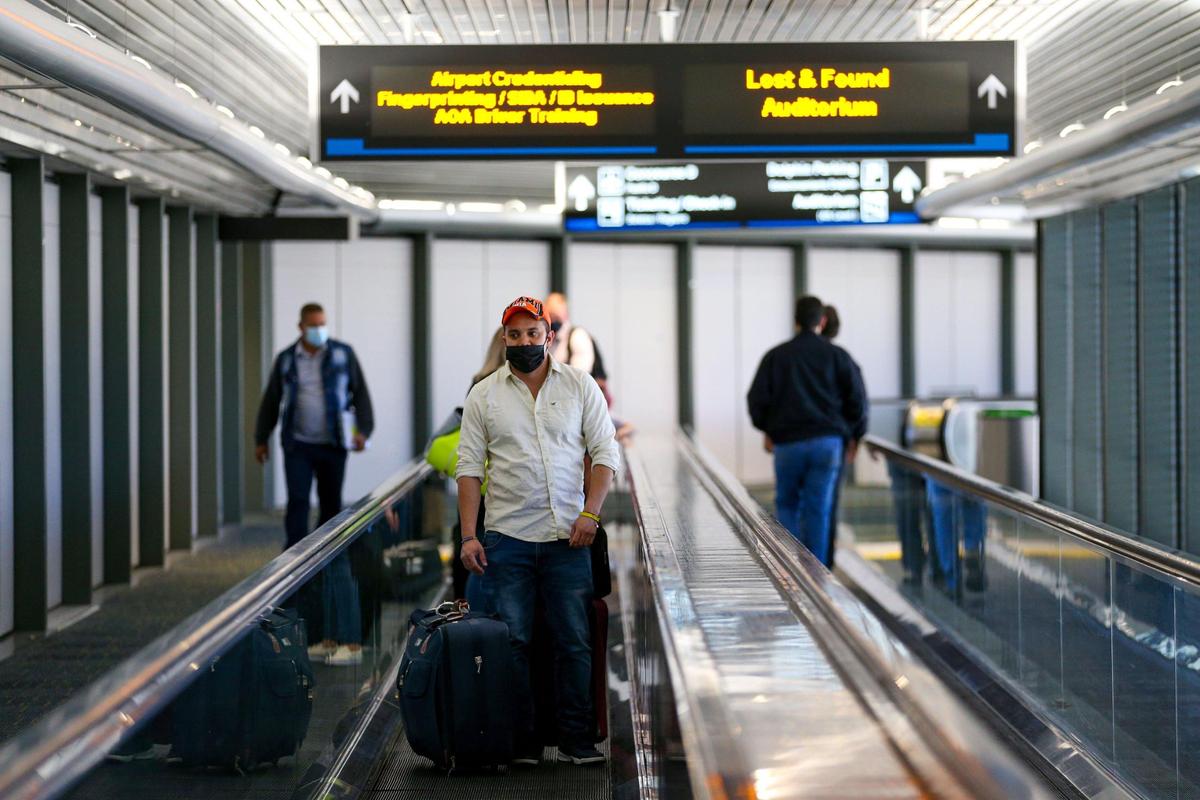 Travelers carry thier luggage as they use the moving walkway at Miami International Airport in Miami, Florida, on Monday, November 22, 2021.
