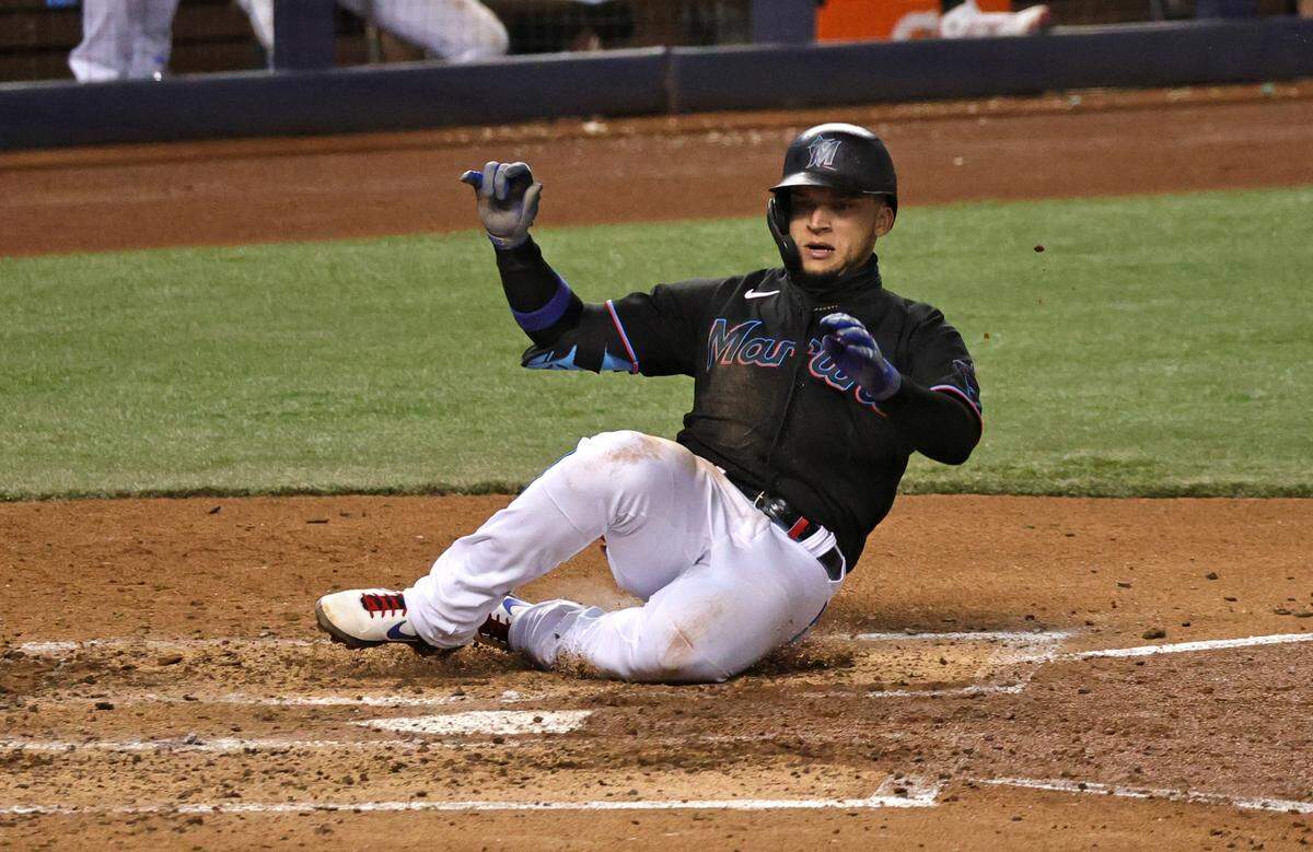 Miami Marlins third baseman Isan Diaz (1) slides safely into home on a RBI single by teammate Marlins second baseman Jon Berti (5) during the fourth inning of their baseball game against the Atlanta Braves at loanDepot park on Friday, June 11, 2021 in Miami, Florida.