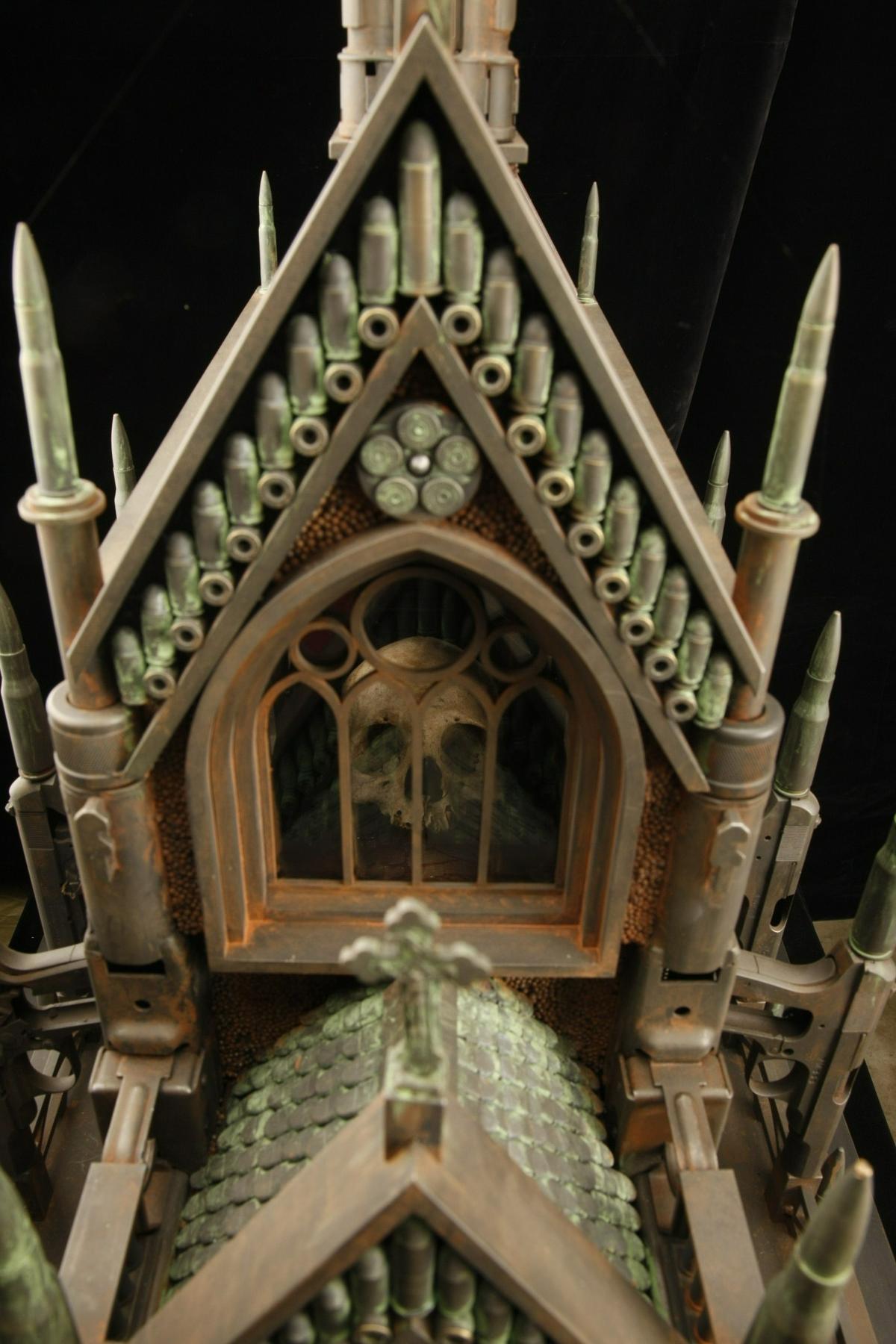 A real human skull sits inside “Gothic Mausoleum,” a sculpture by artist Al Farrow. The mausoleum work is made of recycled bullets, casings and guns.