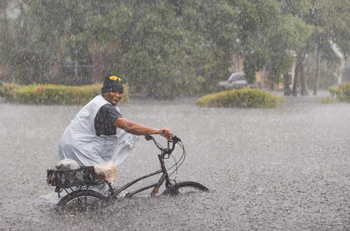 Leon rides his bike down a flooded street in the Edgewood neighborhood on Thursday, April 13, 2023, in Fort Lauderdale, Fla. A torrential downpour severely flooded streets partially submerging houses and cars across South Florida.