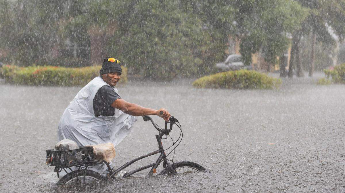 Leon rides his bike down a flooded street in the Edgewood neighborhood on Thursday, April 13, 2023, in Fort Lauderdale, Fla. A torrential downpour severely flooded streets partially submerging houses and cars across South Florida.