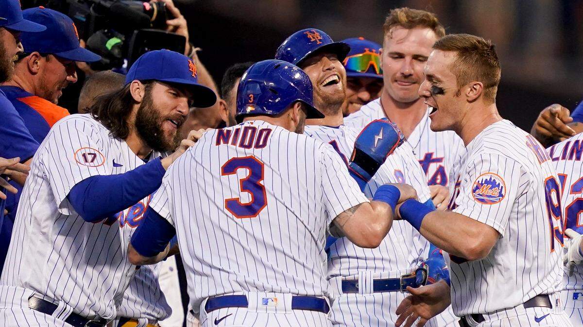 New York Mets catcher Tomas Nido (3) and center fielder Brandon Nimmo, center right, celebrate with their teammates after Nimmo reaches on an infield fielding error to allow the game-winning run by Nido in the tenth inning of a baseball game against the Miami Marlins, Saturday, July 9, 2022, in New York. (AP Photo/John Minchillo)