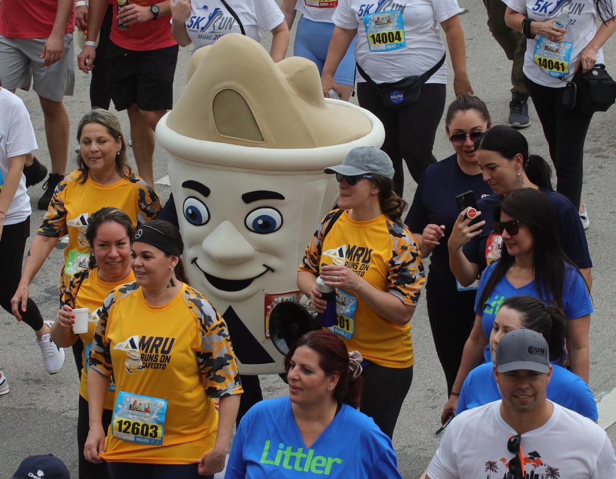 A runner dressed in costume joins a group as the road remains dry while starting the 3.5 mile run under gray skies. More than 9897 runners from 496 companies competed in the Mercedes-Benz Miami Corporate Run, a 3.5-mile team event in which runners/walkers represent their companies or industry-related categories on Thursday, April 28, 2022.