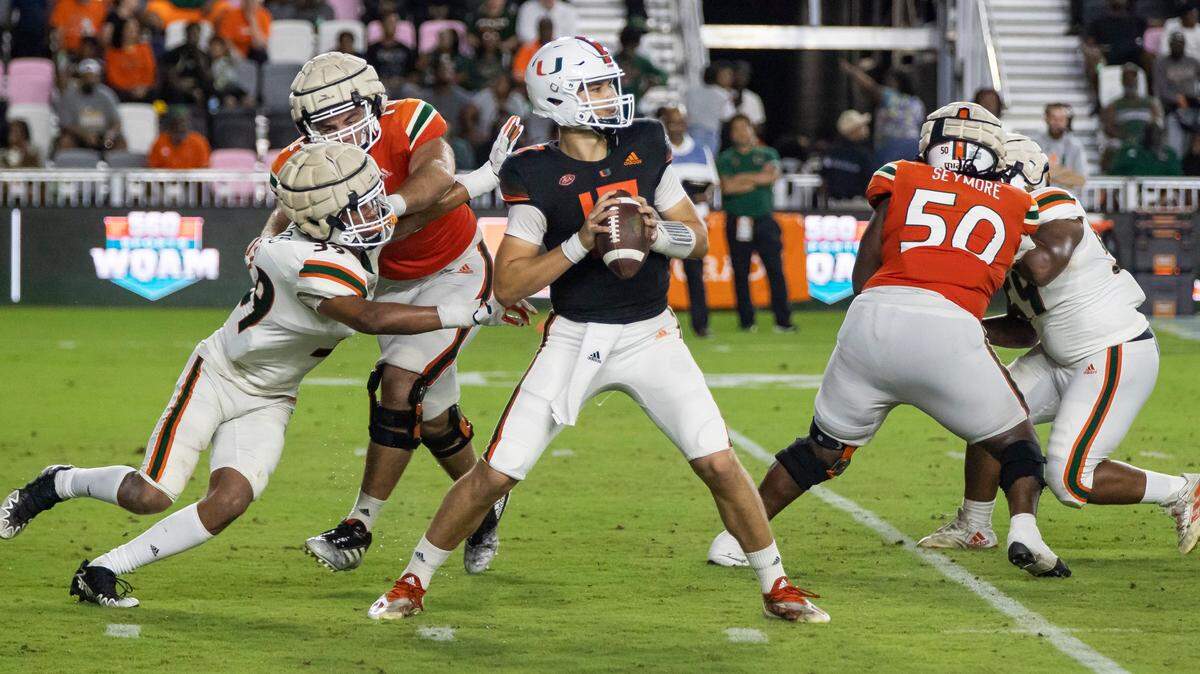 Miami Hurricanes quarterback Emory Williams (17) looks to pass the ball as Miami Hurricanes defensive lineman Cyrus Moss (39) tries to tackle during the fourth quarter of their spring game at DRV PNK Stadium on Friday, April 14, 2023, in Fort Lauderdale, Fla.