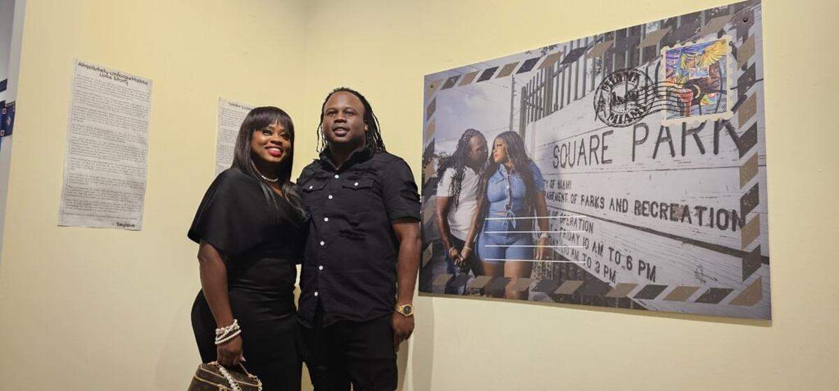 “Unforgettable Love Story” is an art piece by Joe Wesley that tells the love story of married couple Taylisha Scott and Drolin Celestin, an African American woman and a Haitian man, who are seen here posing next to the artwork.