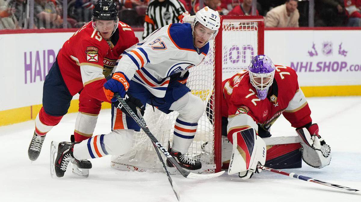 Nov 20, 2023; Sunrise, Florida, USA; Florida Panthers center Anton Lundell (15) reaches for the puck on Edmonton Oilers center Connor McDavid (97) during the first period at Amerant Bank Arena. Mandatory Credit: Jasen Vinlove-USA TODAY Sports